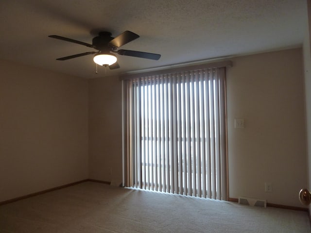 carpeted spare room featuring a textured ceiling, plenty of natural light, and ceiling fan