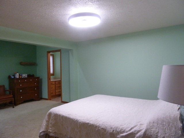 bedroom with light colored carpet, a textured ceiling, and connected bathroom