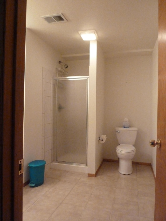 bathroom featuring tile patterned flooring, an enclosed shower, and toilet