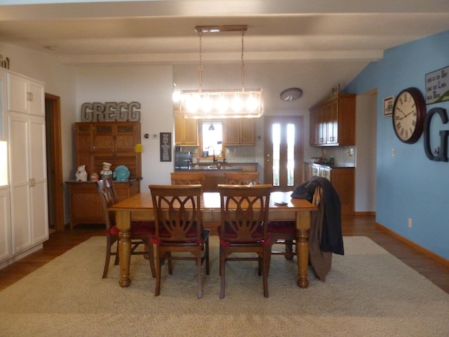 dining room featuring vaulted ceiling with beams, sink, and hardwood / wood-style flooring