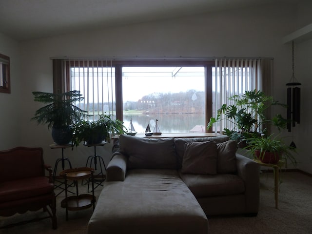 carpeted living room with a water view and vaulted ceiling