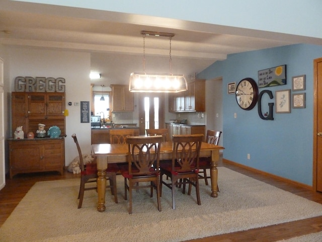 dining space with hardwood / wood-style floors and vaulted ceiling with beams