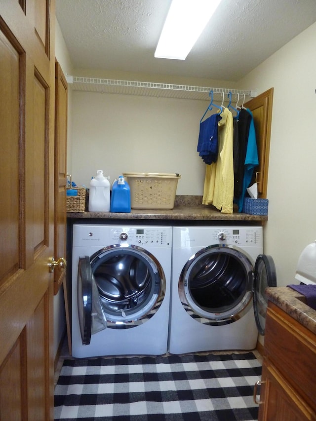 laundry area featuring a textured ceiling and washing machine and clothes dryer