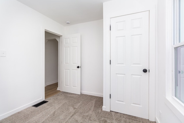 unfurnished bedroom featuring light carpet and a closet