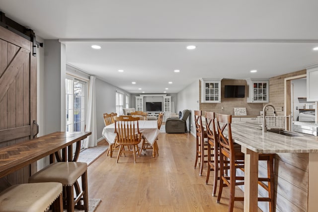 dining area featuring a barn door, sink, and light hardwood / wood-style flooring