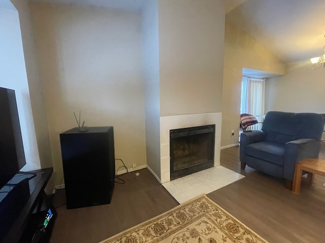 living room featuring a chandelier, lofted ceiling, a fireplace, and light hardwood / wood-style flooring