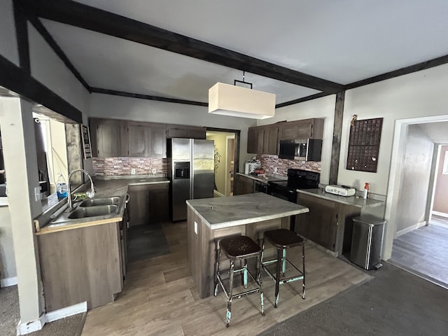 kitchen featuring appliances with stainless steel finishes, backsplash, wood-type flooring, a kitchen island, and a breakfast bar area