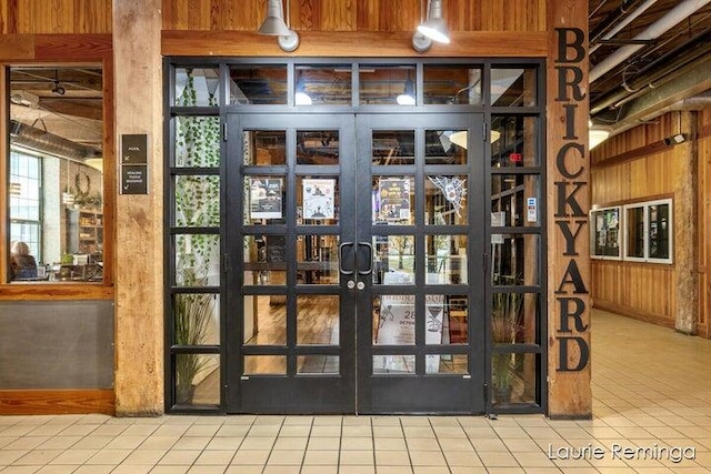 entryway featuring light tile patterned floors, french doors, and wooden walls