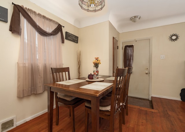 dining room with dark hardwood / wood-style floors and an inviting chandelier