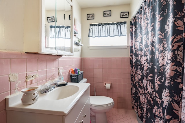 bathroom with walk in shower, tile patterned flooring, toilet, vanity, and tile walls