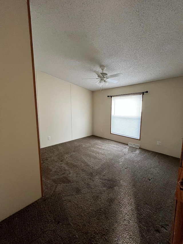 carpeted empty room featuring ceiling fan and a textured ceiling