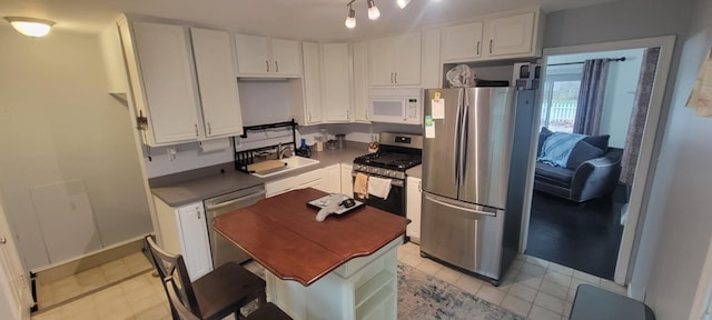 kitchen featuring appliances with stainless steel finishes, white cabinetry, and sink