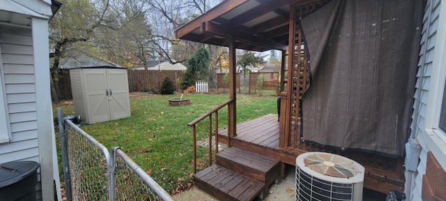 view of yard featuring a wooden deck, a storage unit, central AC unit, and an outdoor fire pit