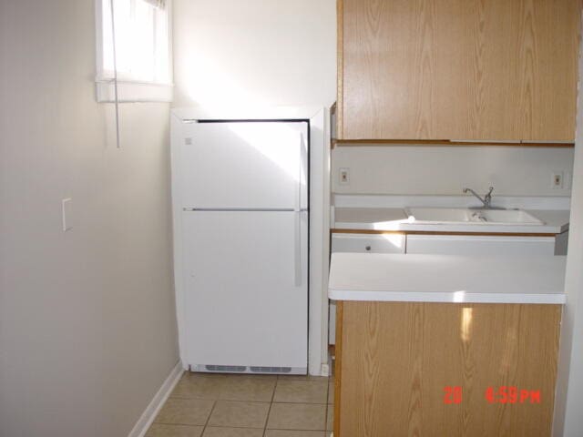 kitchen with sink, white fridge, and light tile patterned flooring