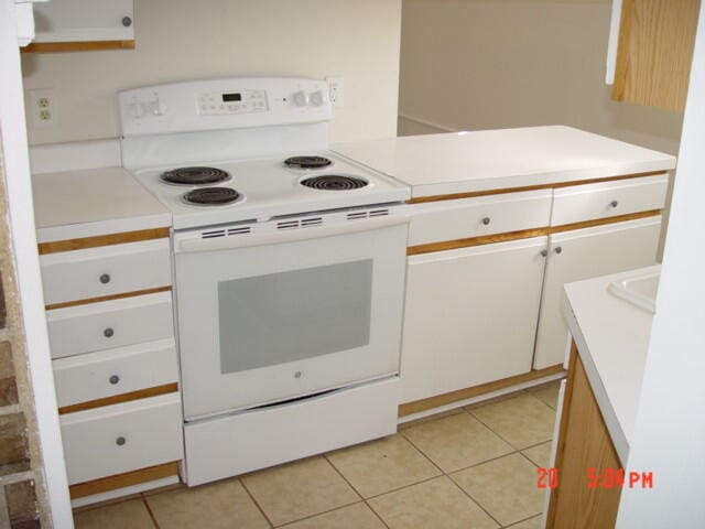 kitchen featuring white range with electric stovetop, white cabinetry, and light tile patterned floors