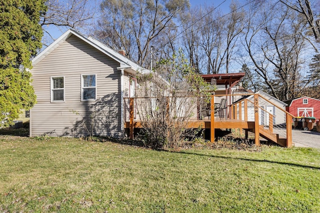 back of house featuring a storage unit, a yard, and a wooden deck