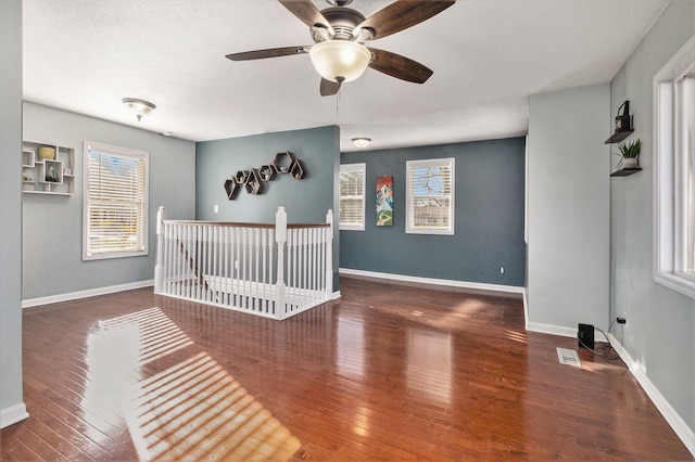 unfurnished bedroom featuring a textured ceiling, ceiling fan, dark hardwood / wood-style flooring, and a crib