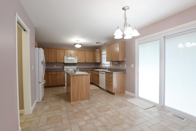 kitchen with white appliances, sink, an inviting chandelier, a kitchen island, and hanging light fixtures