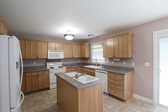 kitchen with light brown cabinets, white appliances, a center island with sink, and sink