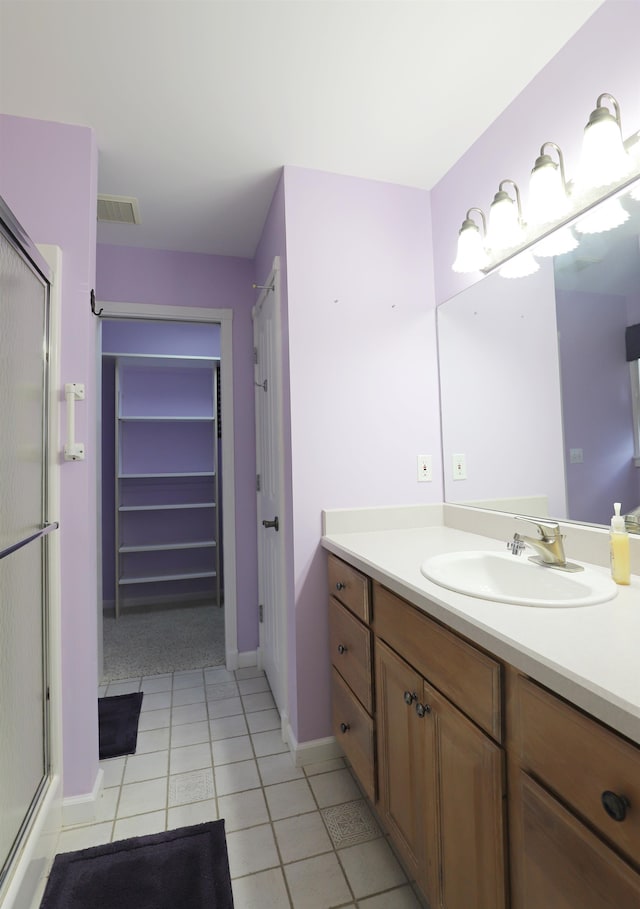 bathroom featuring tile patterned floors, vanity, and a shower with shower door