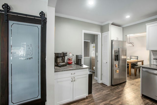 kitchen featuring white cabinetry, dark wood-type flooring, stainless steel appliances, a barn door, and dark stone counters