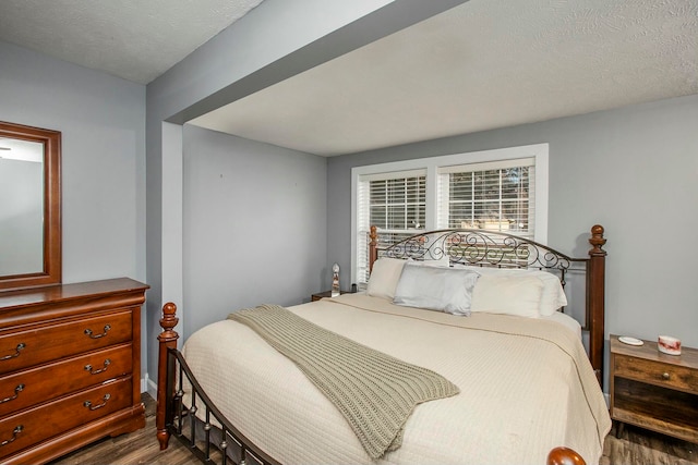 bedroom with a textured ceiling and dark hardwood / wood-style floors