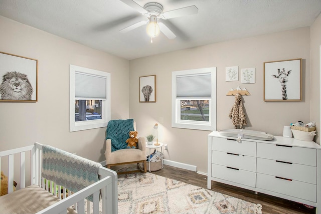 bedroom with ceiling fan, dark hardwood / wood-style flooring, and a crib