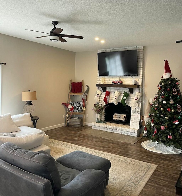 living room featuring ceiling fan, a fireplace, dark wood-type flooring, and a textured ceiling