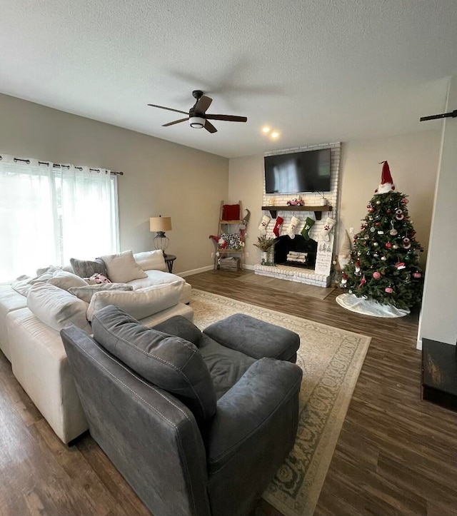 living room featuring a fireplace, ceiling fan, dark hardwood / wood-style flooring, and a textured ceiling