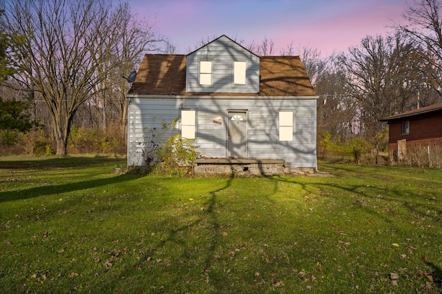 back house at dusk with a lawn