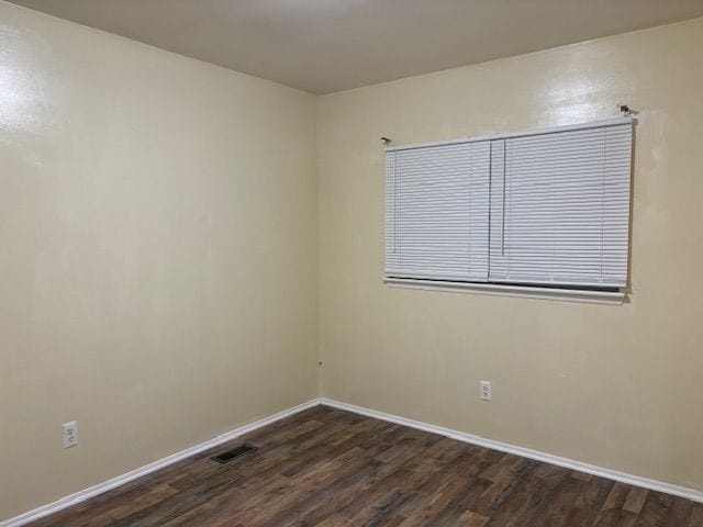 unfurnished room with dark wood-type flooring