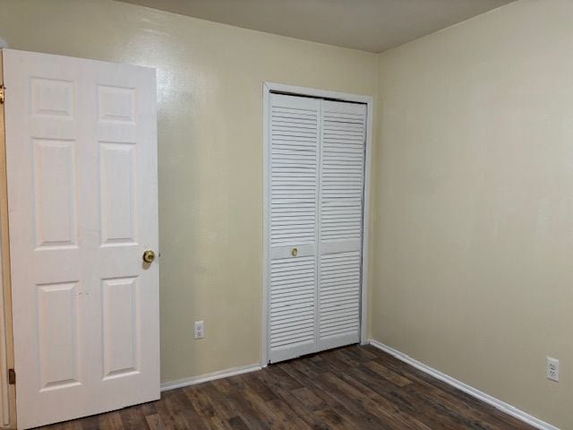 unfurnished bedroom featuring a closet and dark hardwood / wood-style flooring