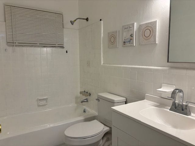 full bathroom featuring vanity, toilet, tiled shower / bath, and tile walls