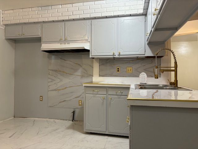 kitchen featuring backsplash, gray cabinetry, and sink