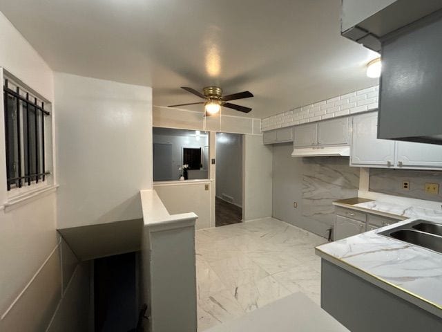 kitchen featuring decorative backsplash, gray cabinets, ceiling fan, and sink