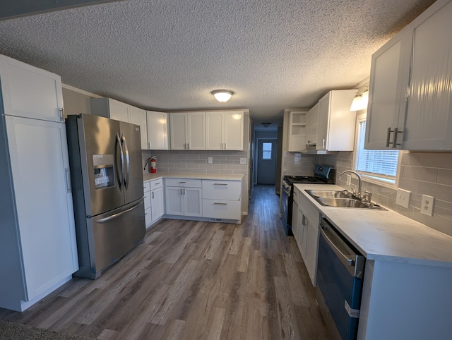 kitchen with decorative backsplash, appliances with stainless steel finishes, sink, light hardwood / wood-style flooring, and white cabinetry