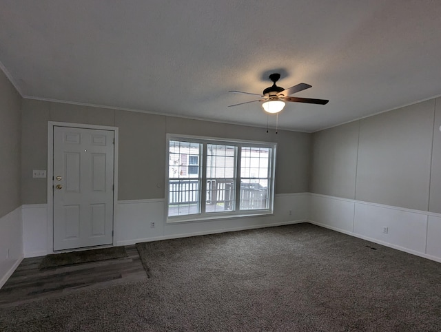 empty room featuring dark colored carpet, a textured ceiling, ceiling fan, and crown molding