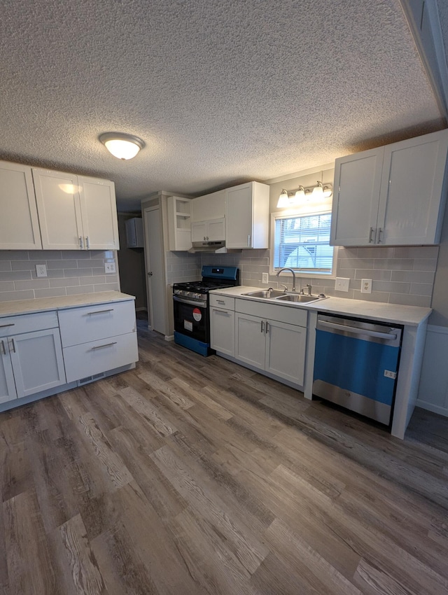 kitchen with gas range oven, hardwood / wood-style floors, white cabinets, and dishwasher