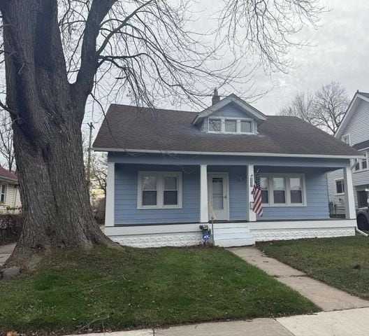 bungalow-style home with covered porch and a front lawn