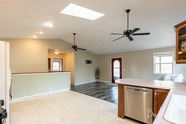 kitchen with lofted ceiling with skylight, ceiling fan, stainless steel dishwasher, and light wood-type flooring