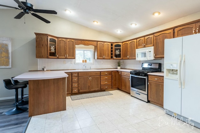 kitchen featuring kitchen peninsula, lofted ceiling, sink, and white appliances