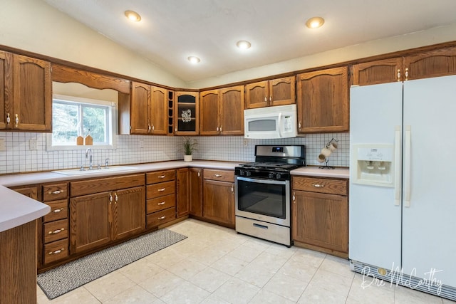 kitchen with tasteful backsplash, lofted ceiling, sink, and white appliances