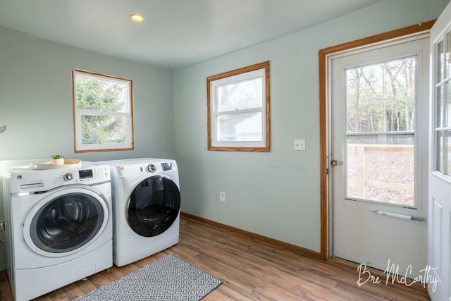 laundry room with light wood-type flooring, a healthy amount of sunlight, and washing machine and clothes dryer