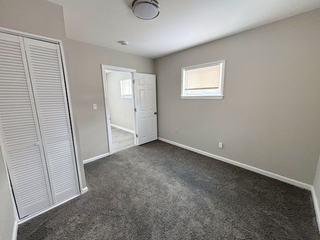 unfurnished bedroom featuring a closet and dark colored carpet