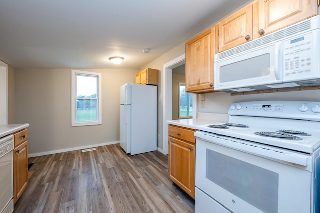 kitchen with dark hardwood / wood-style floors, white appliances, light brown cabinetry, and vaulted ceiling