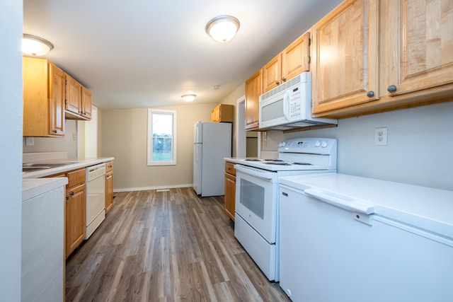 kitchen with sink, hardwood / wood-style floors, white appliances, and light brown cabinets