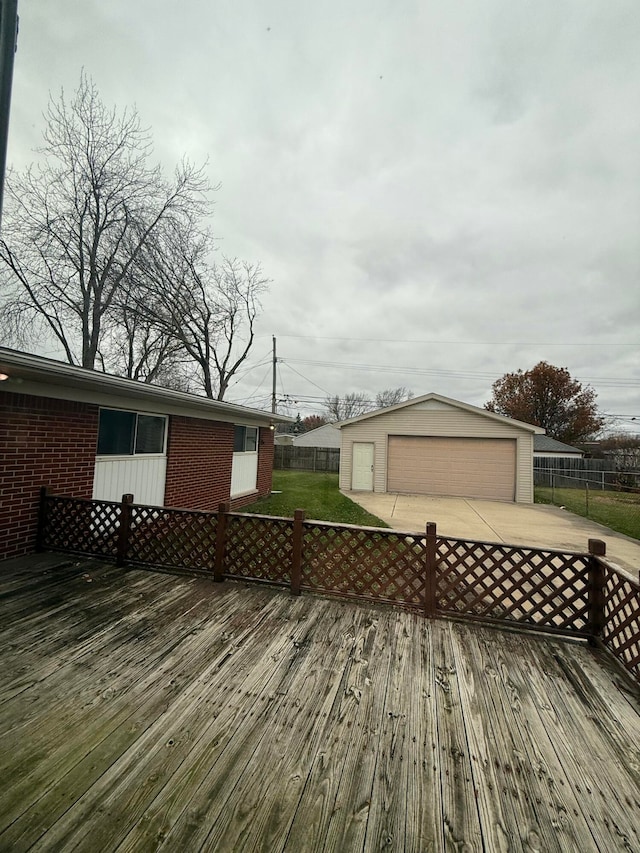 wooden terrace featuring a garage, an outdoor structure, and a lawn