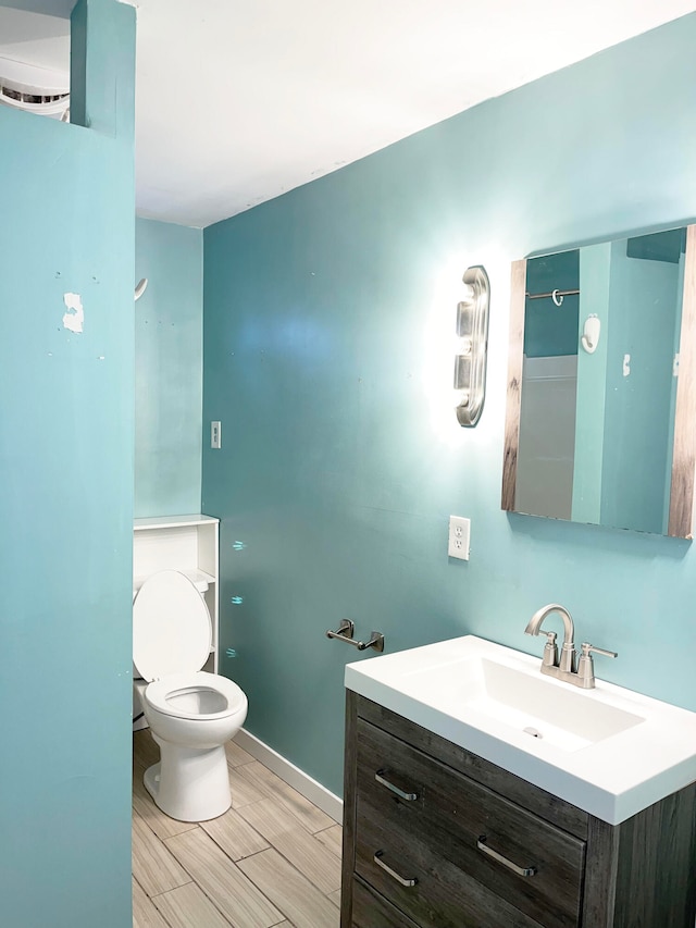 bathroom featuring toilet, wood tiled floor, baseboards, and vanity