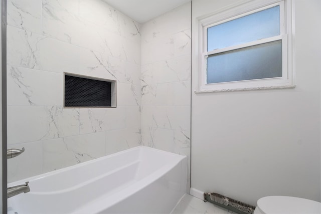 bathroom featuring tiled shower / bath combo and toilet