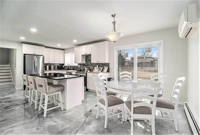 kitchen with pendant lighting, appliances with stainless steel finishes, white cabinetry, a baseboard heating unit, and a wall mounted AC